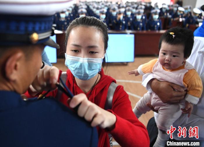 新消防員楊振的妻子彭莉與女兒現(xiàn)場見證丈夫加入“火焰藍(lán)”的神圣時刻?！⒅铱?攝