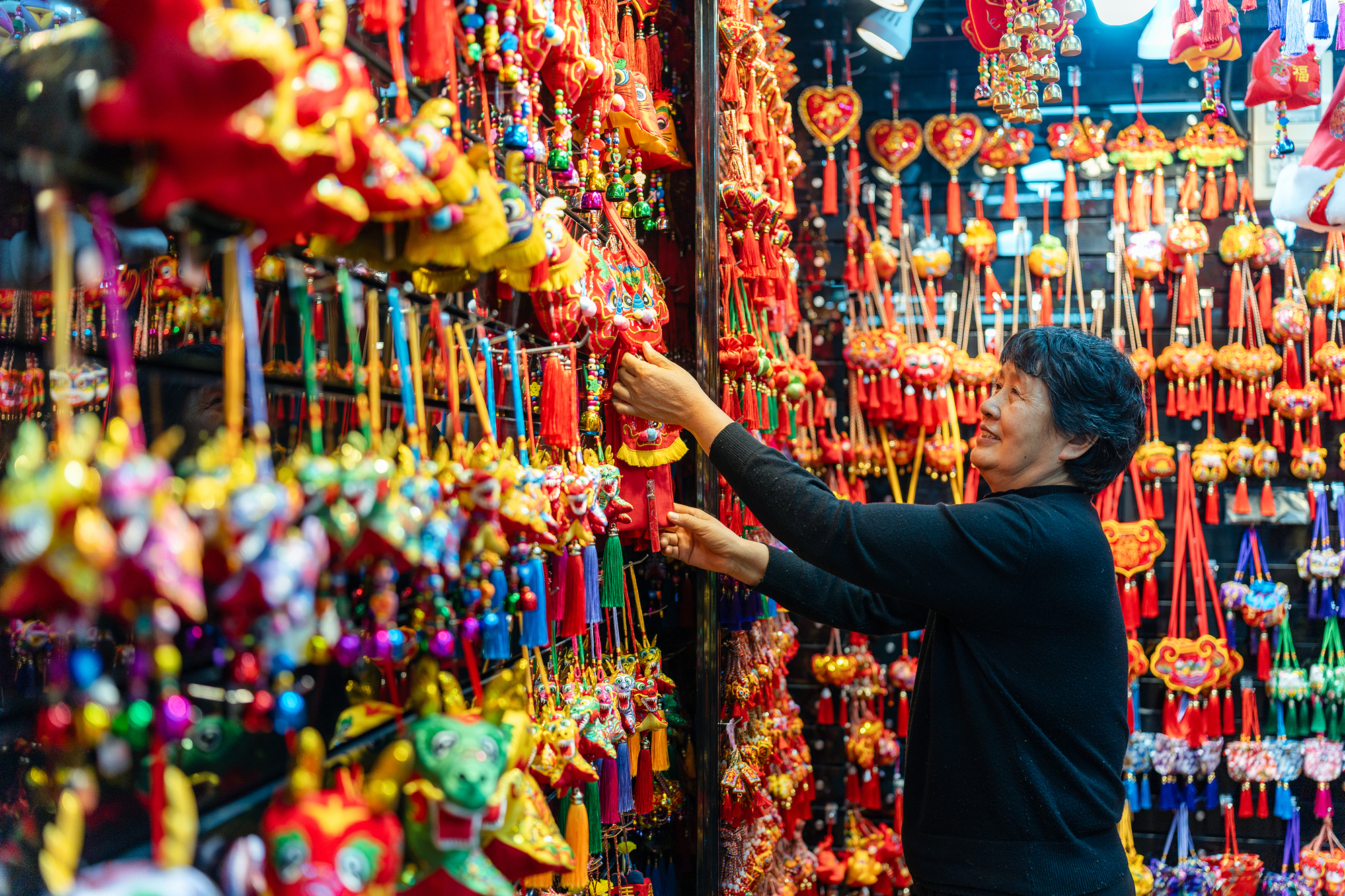 2023年12月11日，金華義烏國際商貿城，龍年喜慶用品掛滿攤位，顧客正在挑選中。