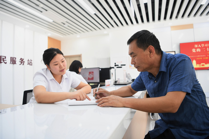 2023年5月23日，河北雄安新區(qū)容東片區(qū)南文營(yíng)社區(qū)居民（右）在社區(qū)便民服務(wù)站辦理業(yè)務(wù)。